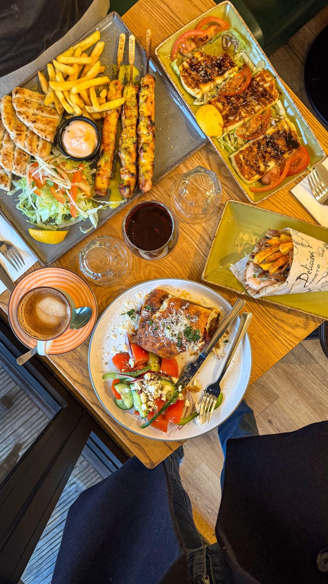 A table of Greek Unique dishes — mixed grill, halloumi, gyros wrap and moussaka